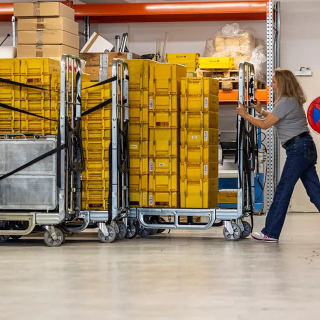 Frau schiebt Wagen mit gelben Boxen